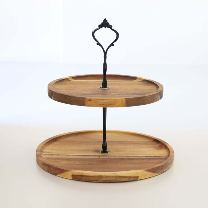 Acacia wood two-tier cake stand with a black metal handle and rod.