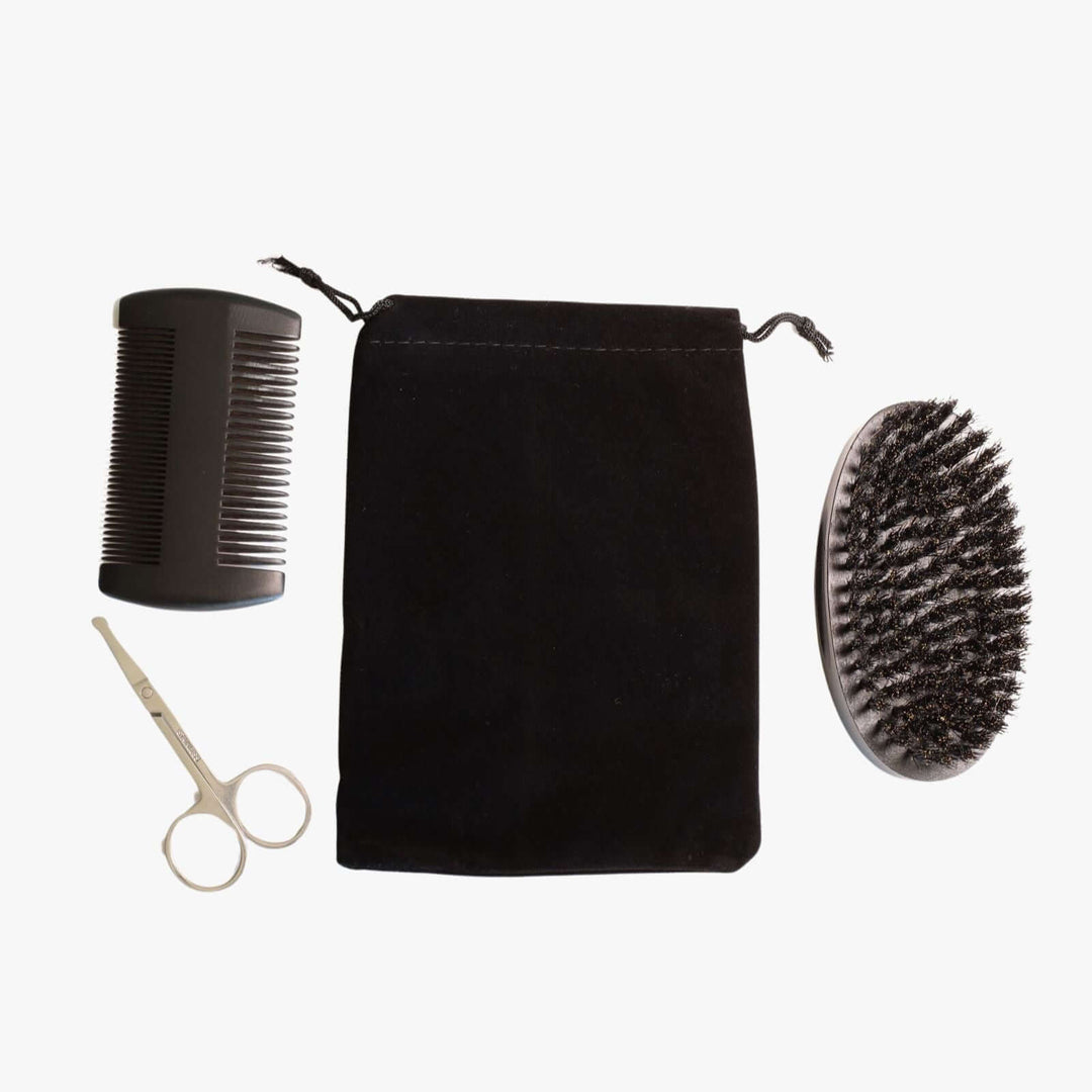Beard grooming kit consisting of a double-sided comb, small scissors, a brush, and a black velvet pouch.