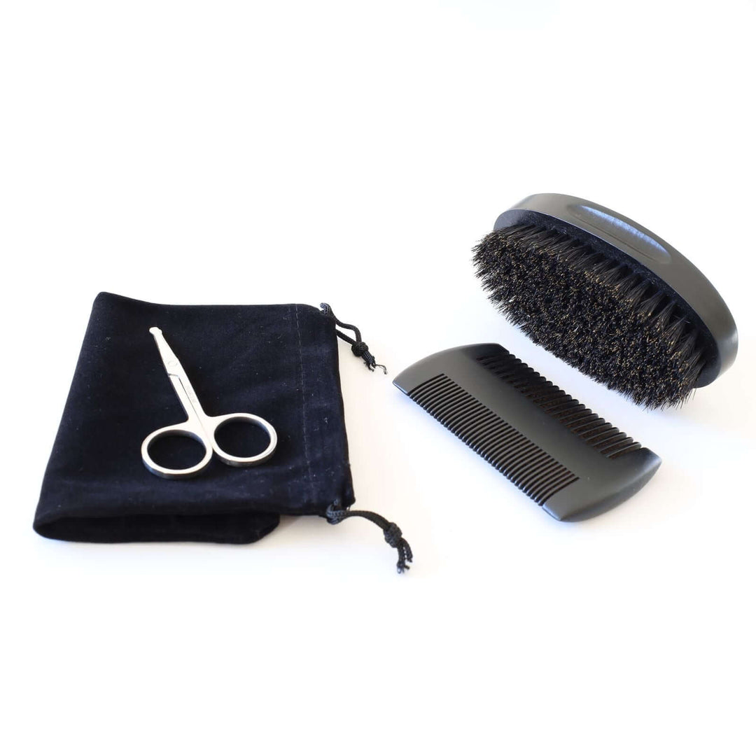 Beard grooming kit consisting of a double-sided comb, small scissors, a brush, and a black velvet pouch.