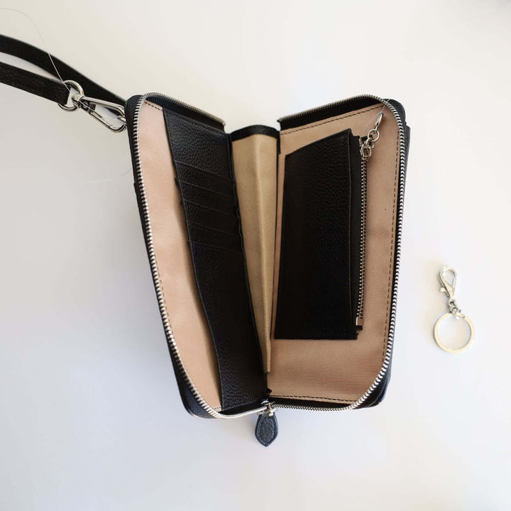 Inside the black pebbled leather phone crossbody wallet. We can see the 5 leather card compartments, together with the bill compartment the leather coin pocket and the detachable keyring. The lining is beige and the leather inside is black.