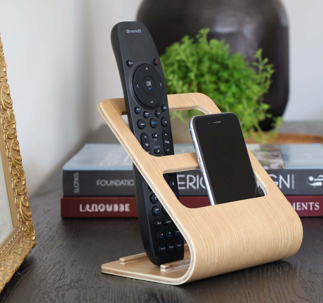 Wooden remote and phone holder shown with a remote control and a phone.