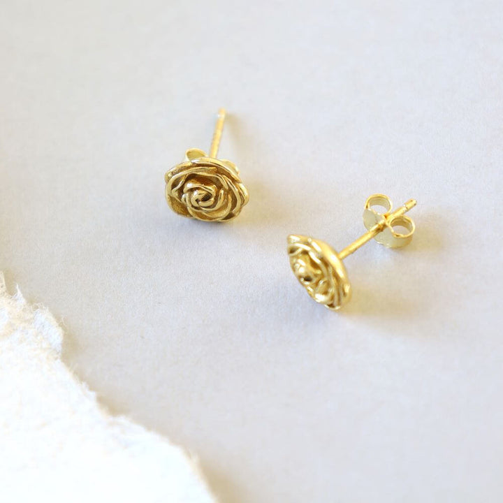 Golden stud earrings designed in the shape of a small rose bud.