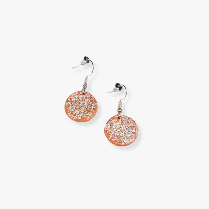 Round orange pendant with glitter hanging form a metal hook.