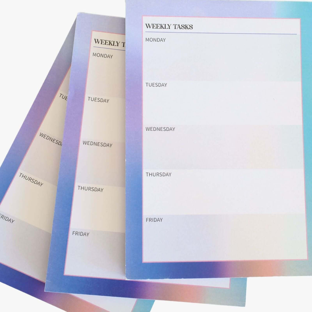 Small weekly planner. Each page is divided into sections for Monday to Friday. The pad features a gradient border with shades of blue and purple. lose up view.