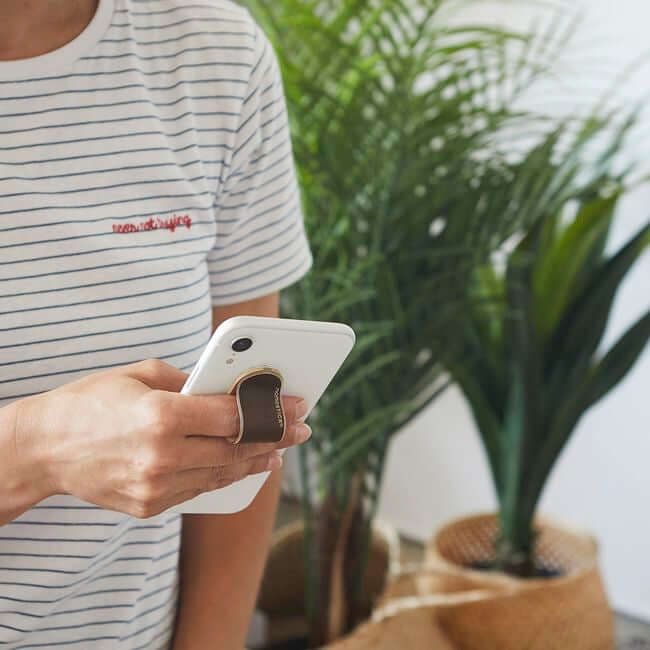 Man holding a phone with a brown phone grip holder.