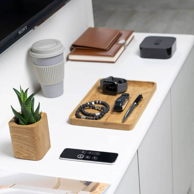 Oak valet tray holding a watch, a pen, two bracelets and a keychain, placed on an office desktop.