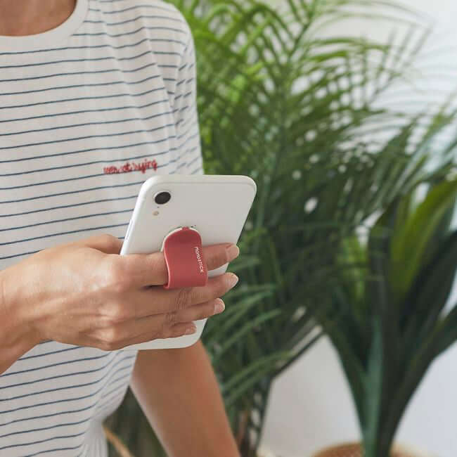 Man holding a phone with a red phone grip holder.