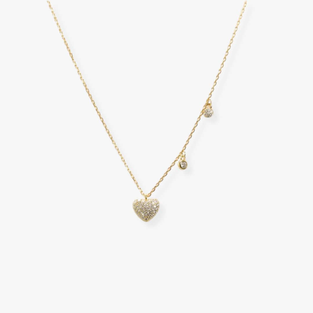 Golden necklace with a heart shaped pendant with cubic zirconia set in pave and, in the right hand side, two round dangles