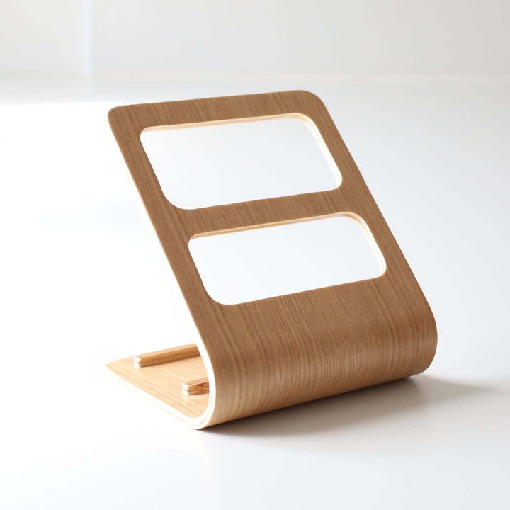 Wooden remote and phone holder with two rectangular cut-outs for holding two separate devices.