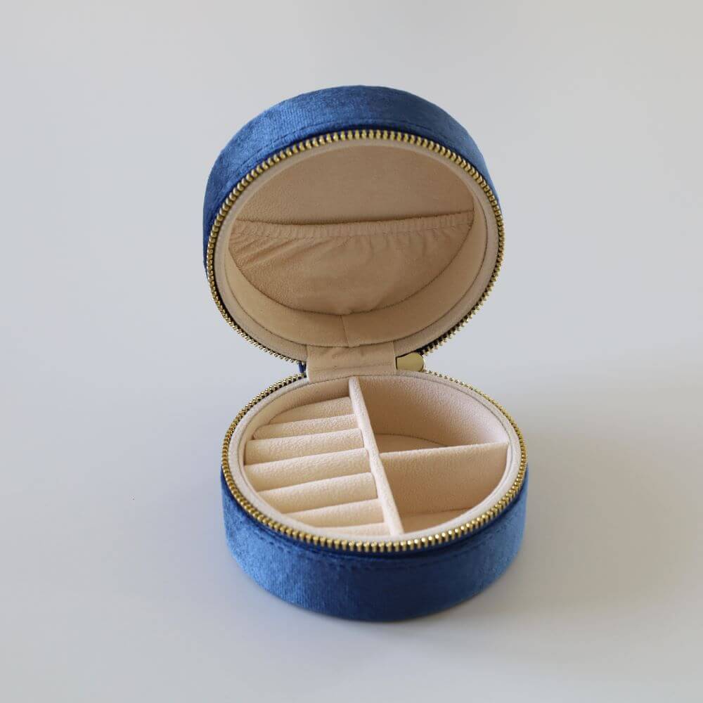 Round blue velvet jewelry box with a gold zipper.
