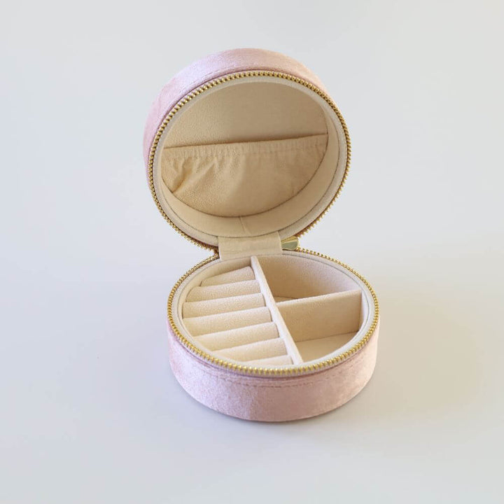 Round pink velvet jewelry box with a gold zipper.