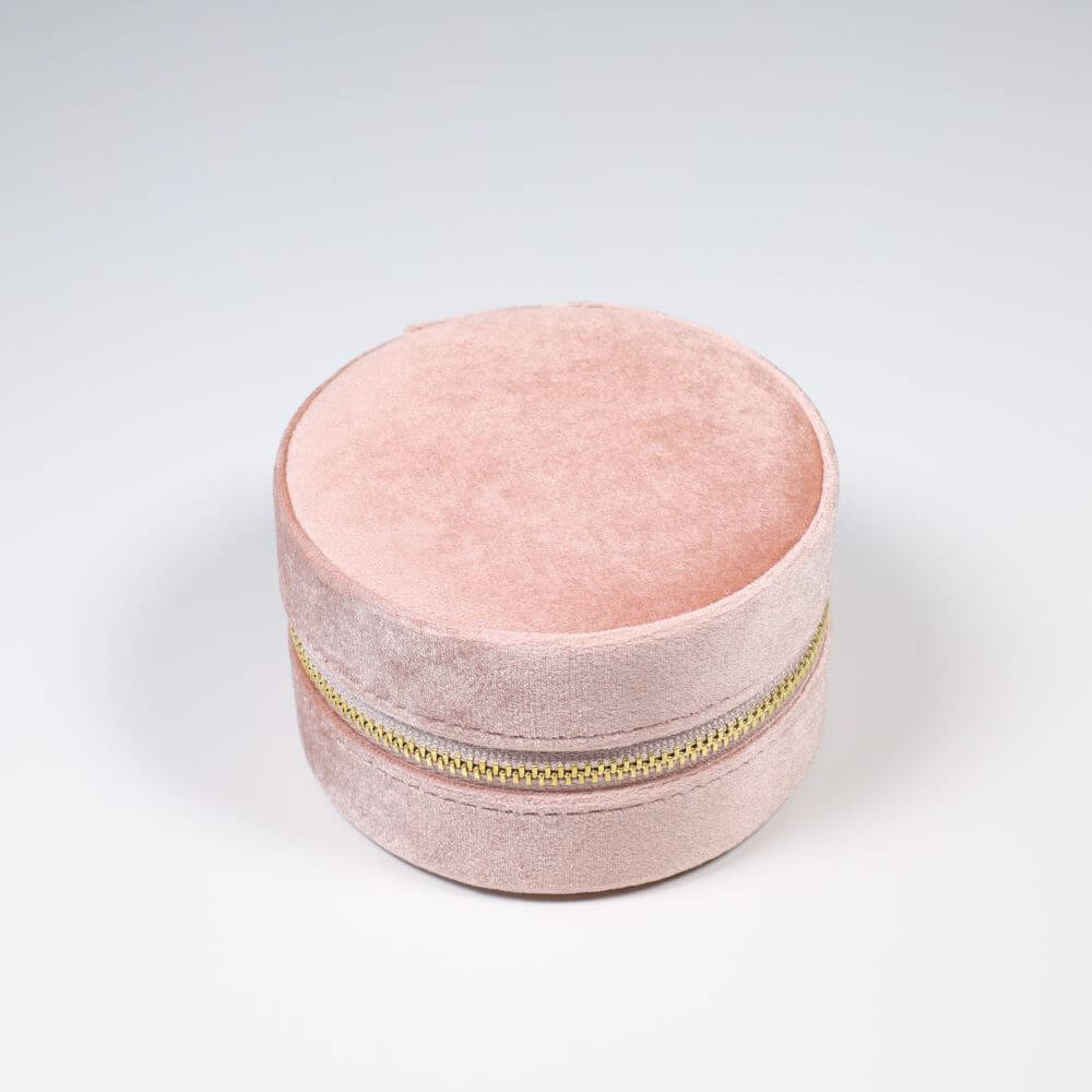 Round pink velvet jewelry box with a gold zipper.