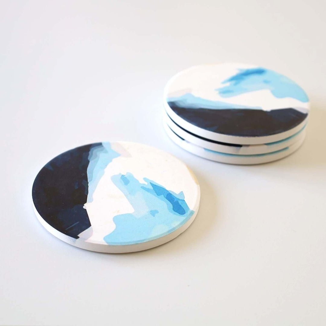 Set of four ceramic blue coasters with a pattern that looks like waves.