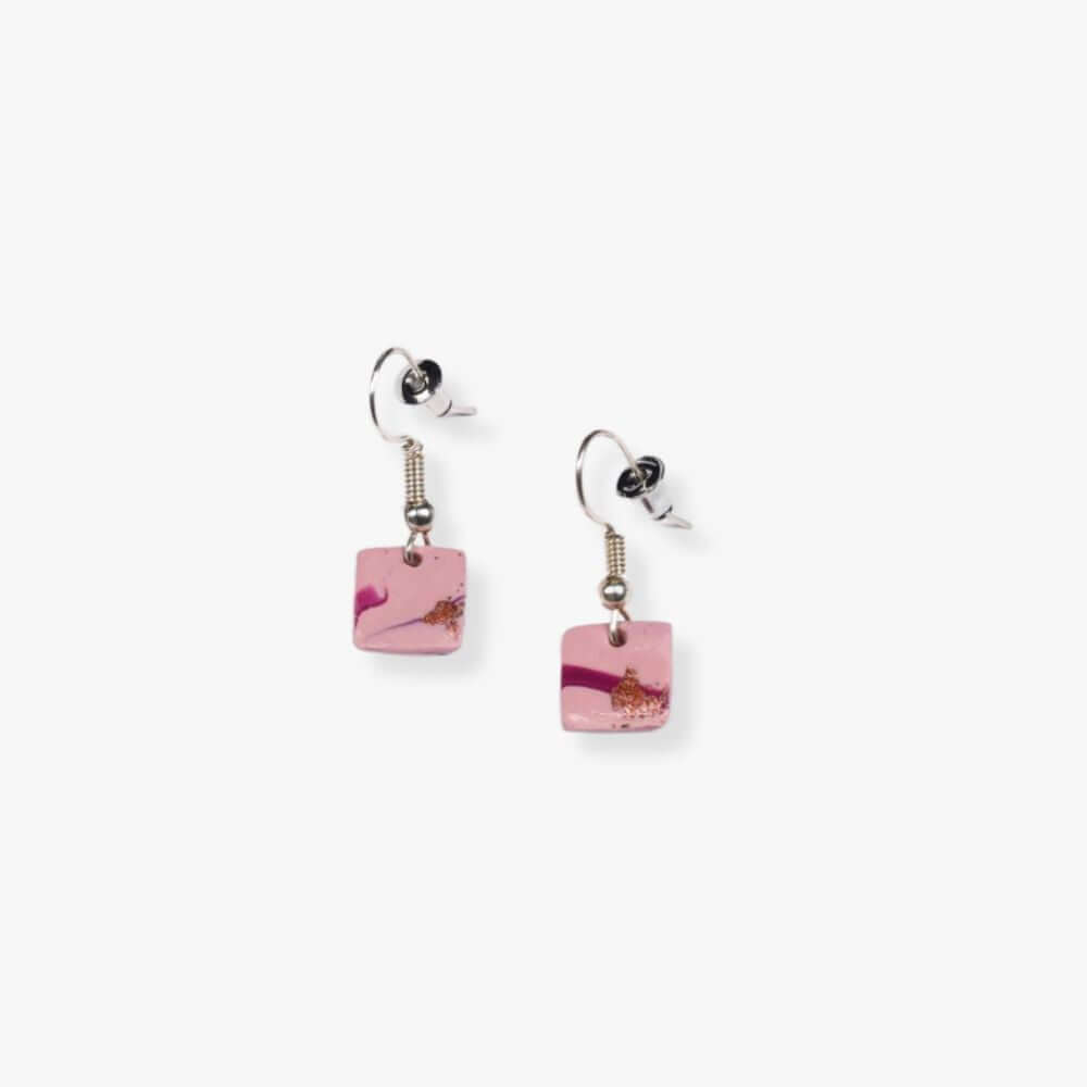 Square pink pendant earrings hanging from a metal hook.