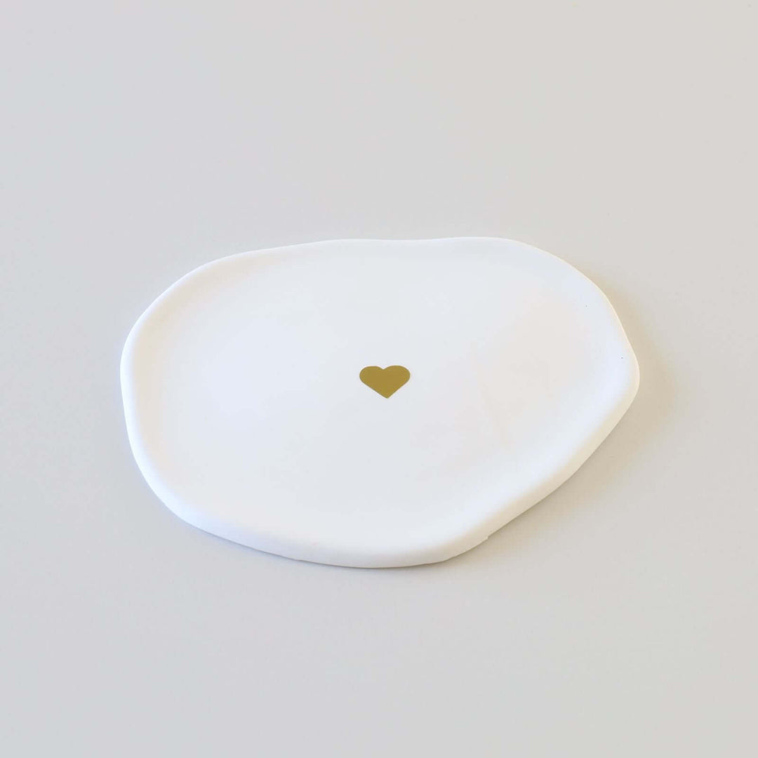 Flat and smooth cloud-shaped ceramic ring dish with a golden heart at the center.