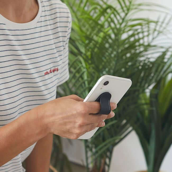 Man holding a phone with a black phone grip holder.