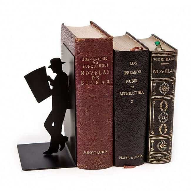 Black metal bookend with a cut out of a man reading a newspaper: view with old books.