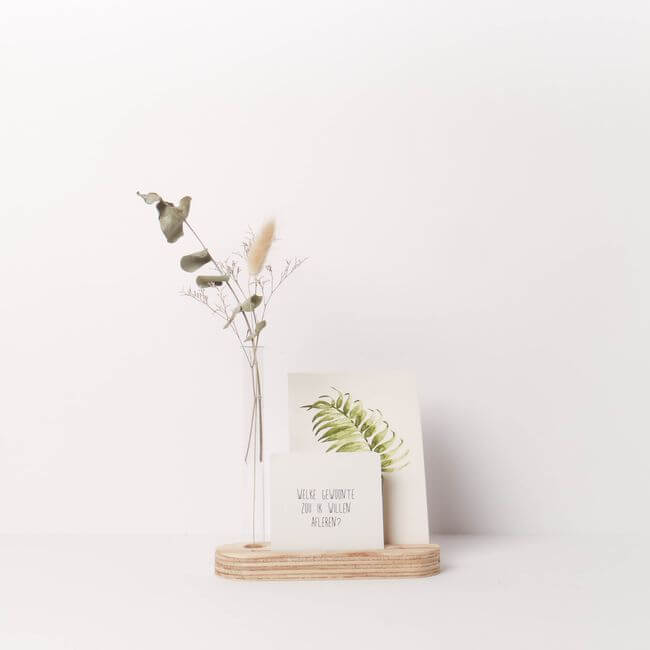 Wooden card display stand with two cards and a bud vase holding dried leaves.