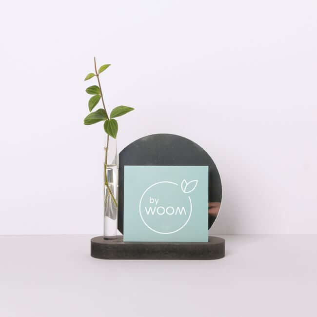 Round edge black display stand holding a bud vase, a card and a mirror.