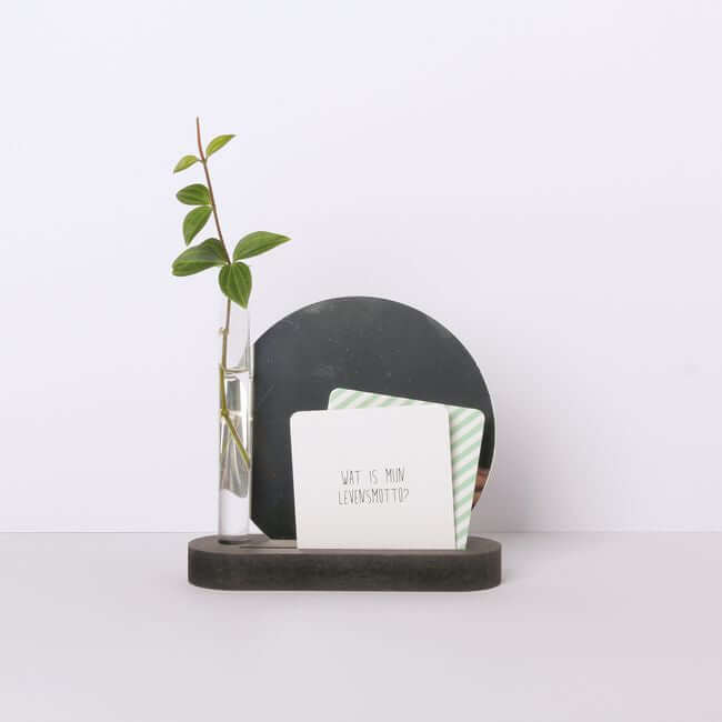 Round edge black display stand holding a bud vase, two small cards and a mirror.