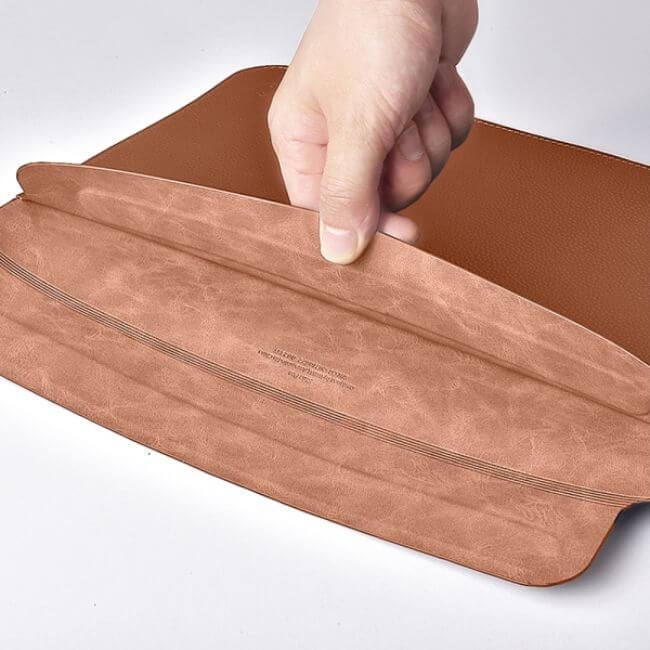 Hand showing the soft finish inside a brown leather sleeve for MacBook Pro 13".