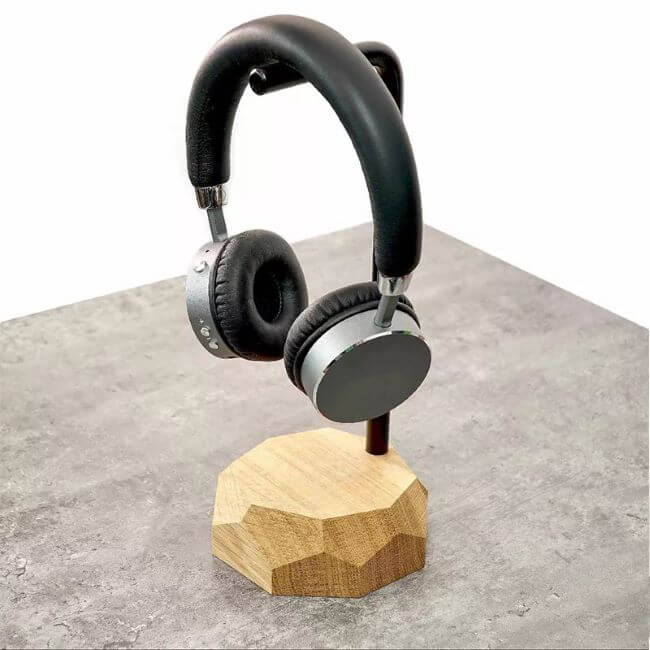 Black headphone hanging on a black metal and natural oak headphone stand.