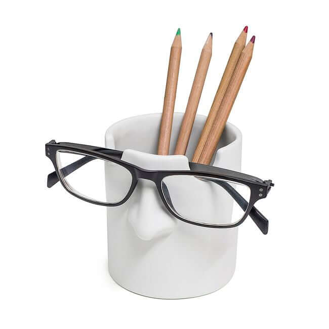 White ceramic pen holder designed to hold one pair of eyeglasses, shown with pencils and black eyeglasses.