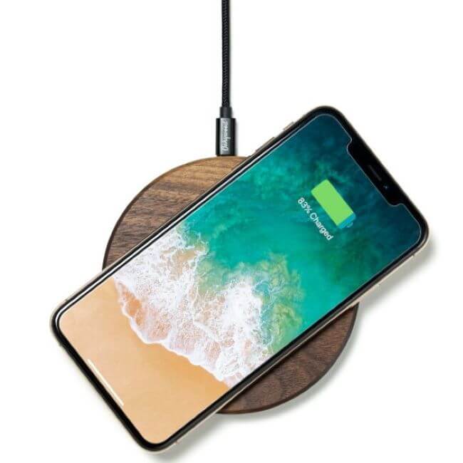 Walnut wireless charging pad with a phone on it.