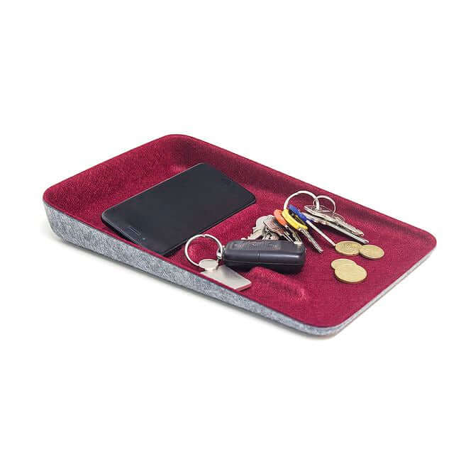 Rectangular valet tray with a gray felt base and a red felt top holding a phone, keys and change.